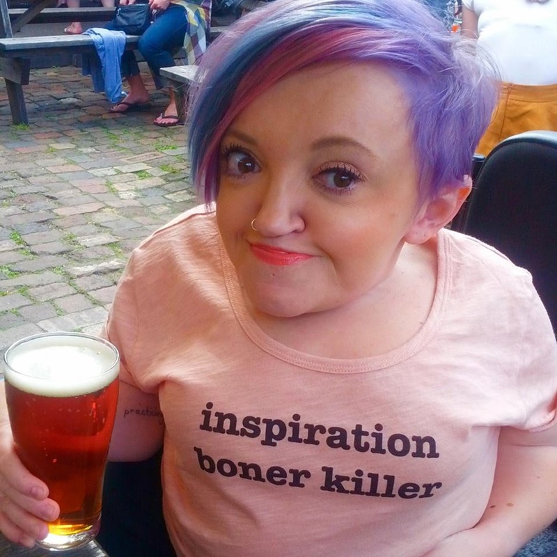 An image of Stella Young holding a beer.  Stella has pink and purple hair and a nose ring and her teeshirt reads 'Inspiration Boner Killer'. 
